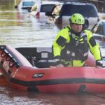 Citywide Disaster Triggers Emergency Powers Rescue worker in an inflatable boat during urban flooding