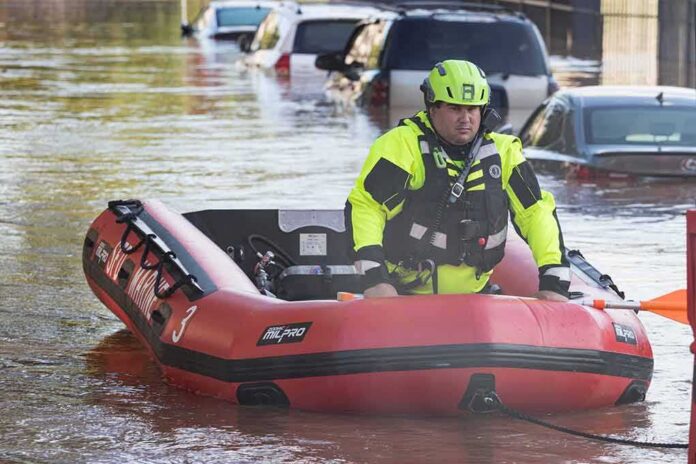 shutterstock_2035377782-1 Rescue worker in an inflatable boat during urban flooding