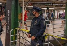 Police officer stands in a subway station near caution tape
