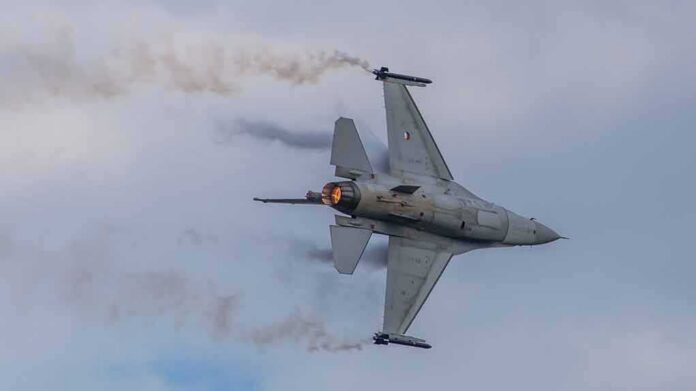 shutterstock_2143879765 Fighter jet banking with afterburner against a cloudy sky