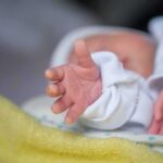 Grand Rapids Shock: Infant Injuries Spark Charges Newborn hand reaching out on a blanket