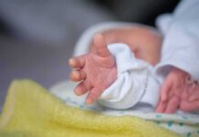 Grand Rapids Shock: Infant Injuries Spark Charges Newborn hand reaching out on a blanket