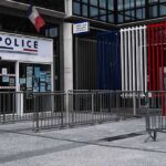 Explosions Shake Macron Trip — Target Unknown Police station entrance with barriers and French flag colors
