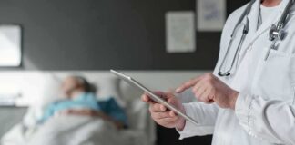 Doctor using tablet beside hospital patient