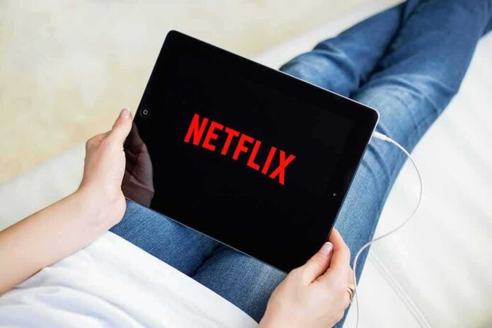 shutterstock_393295279 Person holding a tablet with streaming app on screen