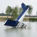 Cold Lake, Dark Night — Congressman Survives How? An abandoned aircraft partially submerged in a calm body of water surrounded by trees