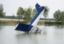 Cold Lake, Dark Night — Congressman Survives How? An abandoned aircraft partially submerged in a calm body of water surrounded by trees
