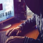 Ghost Students Raid Taxpayer Cash hooded person typing at a computer with multiple monitors