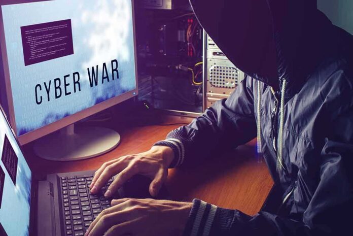 shutterstock_540300310 hooded person typing at a computer with multiple monitors