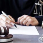 Phone Evidence Tests Mental Illness Defense Judge writing at desk with gavel and Lady Justice statue