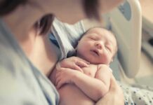 newborn baby sleeping in a parent's arms