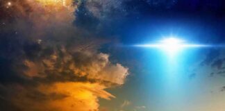 Bright blue light beam over dramatic clouds at dusk