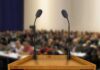 This Campus Speech Fight Came With A Price Podium with two microphones facing a blurred audience