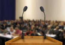 This Campus Speech Fight Came With A Price Podium with two microphones facing a blurred audience