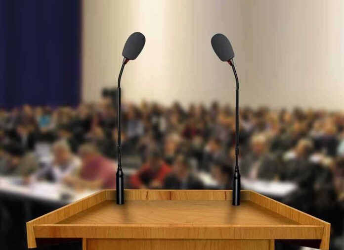 Podium with two microphones facing a blurred audience
