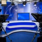State TV Broadcast Targets The President’s Son A television studio setup with cameras and a blue backdrop