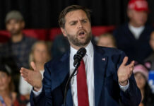 Violent Rhetoric Blast – VP Dragged Into Firestorm Man in suit speaking at a podium