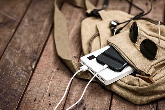 Beige backpack with phone charging on power bank and sunglasses