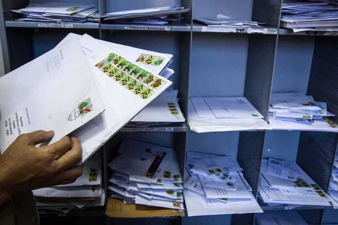 Hands sorting envelopes in a mailroom cubby