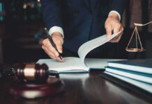 Lawyer signing documents at a desk with gavel and scales