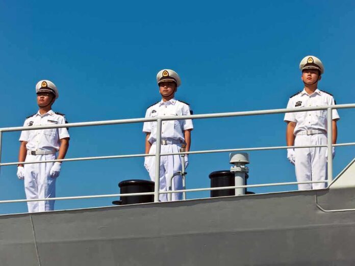 shutterstock_109444004 three naval officers in white uniforms standing on a ship deck