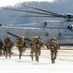 The Last Troops Are Gone. Now Comes the Test Soldiers disembark and walk past a large military helicopter