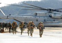 The Last Troops Are Gone. Now Comes the Test Soldiers disembark and walk past a large military helicopter