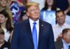 Donald Trump at a rally wearing a dark suit and blue tie