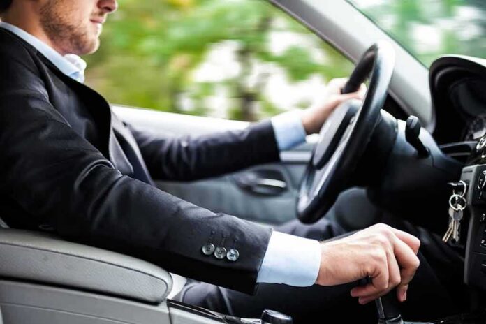 shutterstock_116279278 Driver in a suit operating a car
