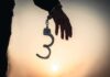 Hand with open handcuff in silhouette at sunset