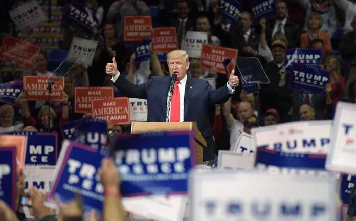 Donald Trump speaks at a rally, giving two thumbs up