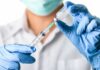 Healthcare worker drawing vaccine from vial with syringe