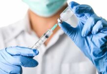 Healthcare worker drawing vaccine from vial with syringe