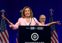woman at podium with arms outstretched during speech