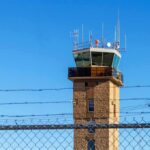 Runway Overrun Mystery: Wind Warning Missing Airport control tower behind chain-link and barbed-wire fence