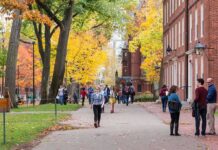Walter Jones and students walking on a leafy campus path in autumn