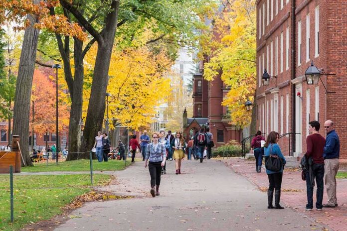 Walter Jones and students walking on a leafy campus path in autumn