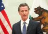 Gavin Newsom speaking at a podium with U.S. and California flags behind him