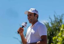 Man in white cap speaking into a microphone outdoors