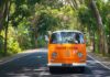 Orange vintage van driving on a tree-lined road