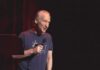 Bill Maher performing stand-up with a microphone on stage